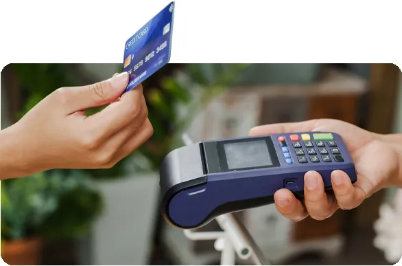 Hand taps credit card on payment machine held by another hand.